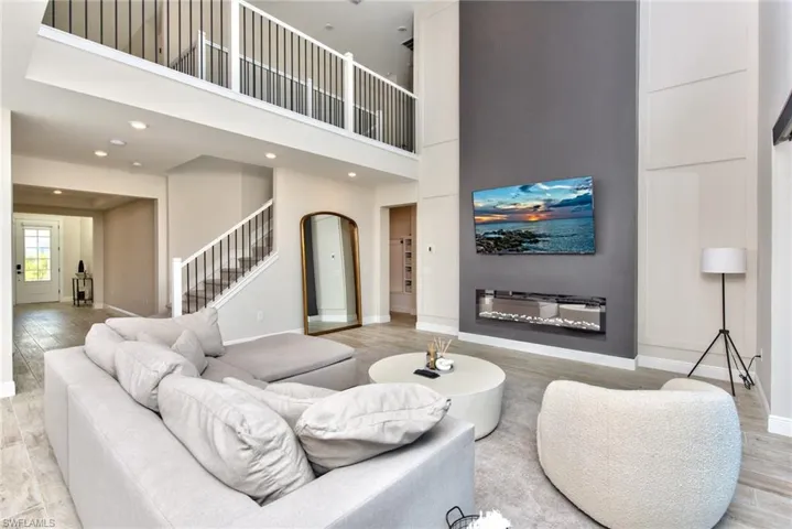 Living room featuring light wood finished floors, a towering ceiling, stairway, arched walkways, and recessed lighting