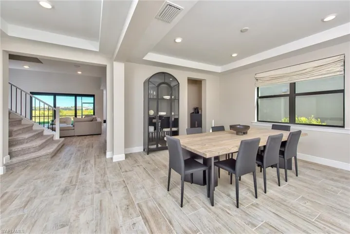 Dining area featuring a raised ceiling, wood tiled floors, recessed lighting, and stairs