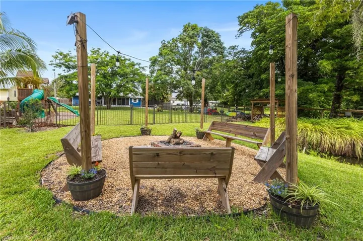 View of yard featuring a playground, firepit, woodshed