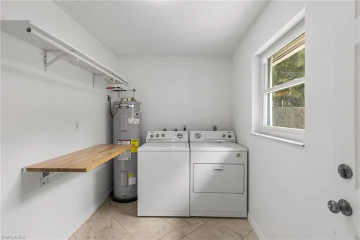 Laundry area with electric water heater, washing machine and clothes dryer, and a textured ceiling