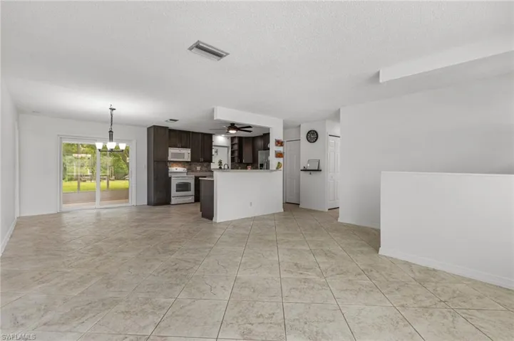Unfurnished living room featuring a chandelier, a textured ceiling, and ceiling fan