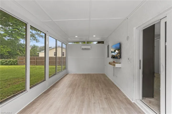 Unfurnished sunroom featuring a wall unit AC