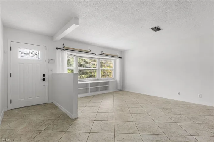 Foyer entrance with a textured ceiling and light tile patterned floors