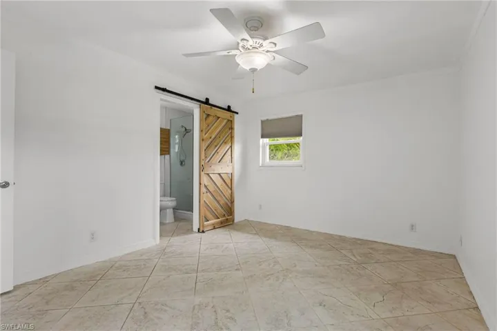 Spare room featuring a barn door, ceiling fan, and ornamental molding