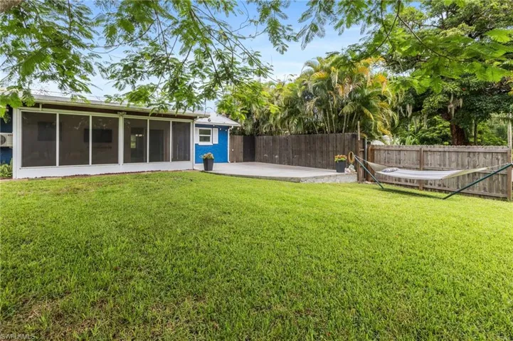 Fenced backyard featuring a sunroom and a patio area