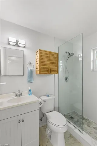 Bathroom with a walk in shower, vanity, and marble look tile flooring