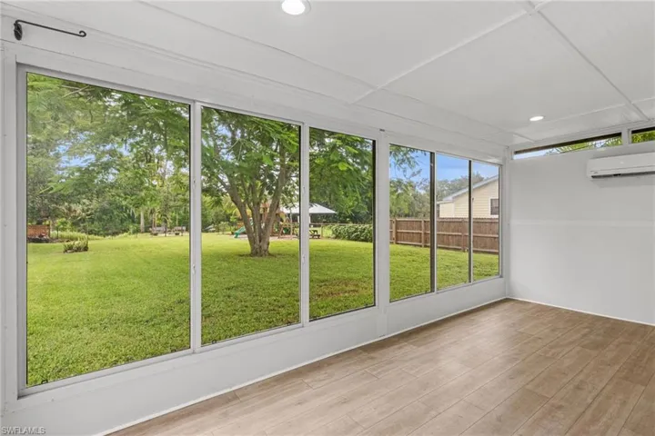 Unfurnished sunroom with an AC wall unit