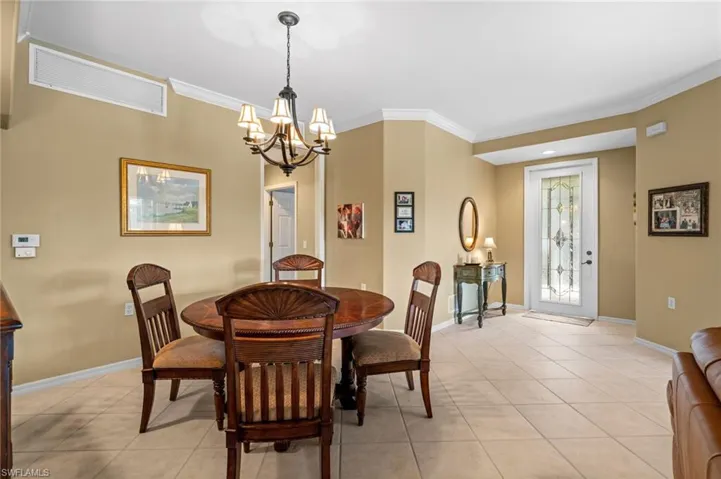 Dining room featuring light tile patterned floors, a chandelier, and ornamental molding