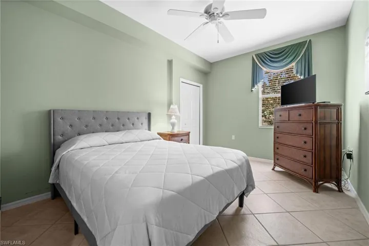 Bedroom with ceiling fan, light tile patterned flooring, and a closet