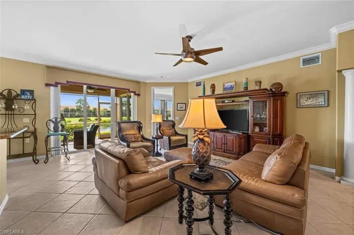 Living room featuring a ceiling fan, light tile patterned flooring, and crown molding