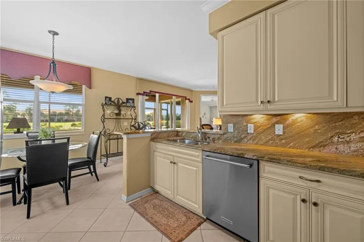 Kitchen featuring dishwasher, cream cabinetry, dark stone counters, pendant lighting, and a peninsula