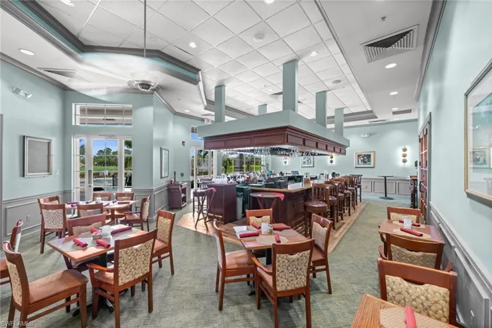 Dining area featuring a wainscoted wall, a decorative wall, a bar, crown molding, and carpet