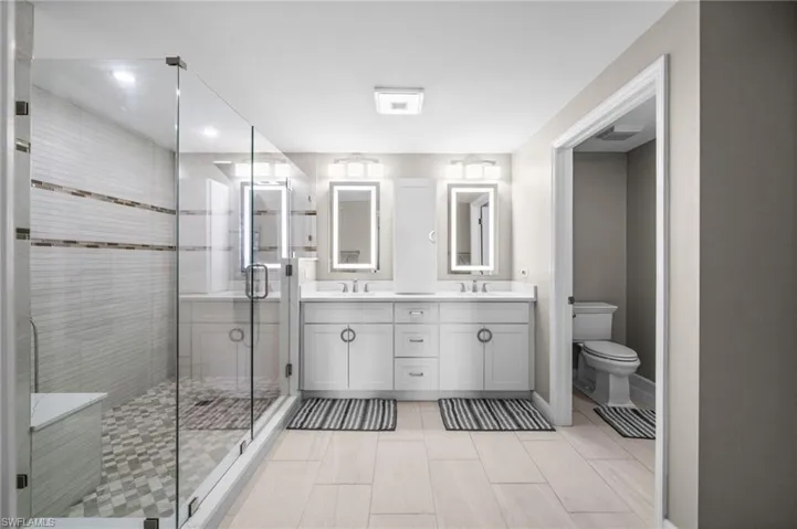 Full bath featuring double vanity and a stall shower