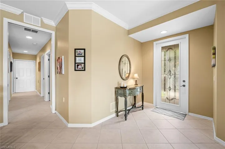 Entryway with light tile patterned floors, recessed lighting, and ornamental molding