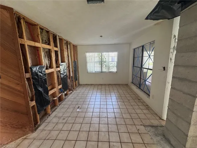 Tiled flooring, multiple windows providing natural light, exposed wood framing, and an exposed concrete block wall