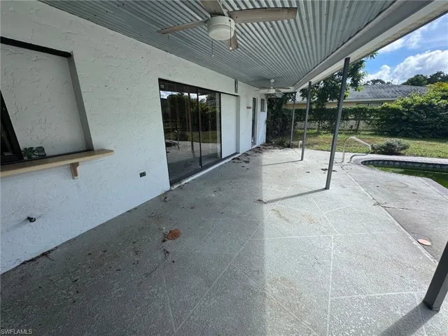 Covered patio with a corrugated metal ceiling, multiple ceiling fans, and an integrated counter surface