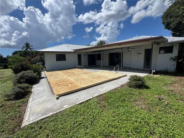 Expansive backyard featuring a concrete patio, covered outdoor living area, and a metal roof