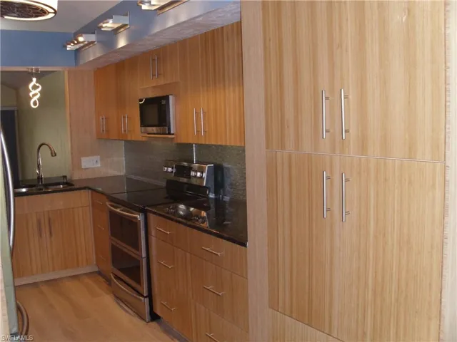 Kitchen featuring dark stone counters, stainless steel appliances, modern cabinets, and decorative backsplash