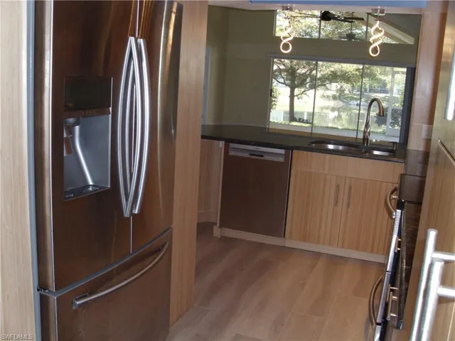 Kitchen with stainless steel appliances, dark stone counters, light wood-style flooring, modern cabinets, and light wood finish cabinetry