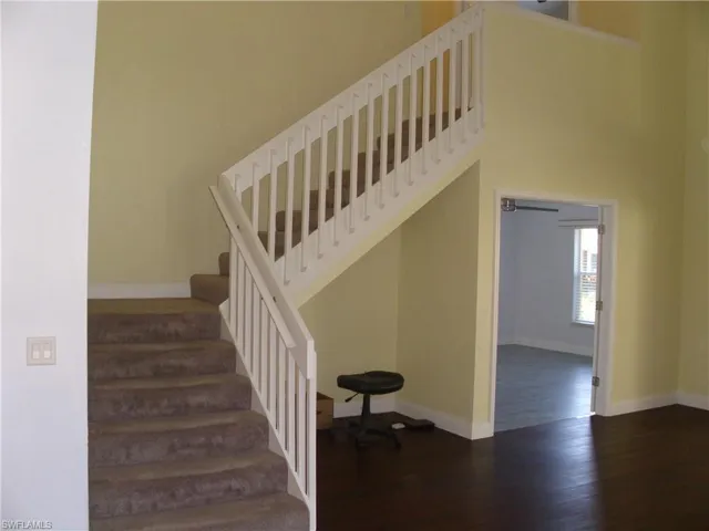 Staircase featuring wood finished floors and a high ceiling