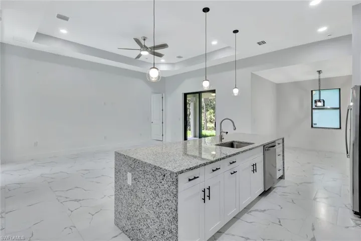 Kitchen with appliances with stainless steel finishes, ceiling fan, white cabinetry, recessed lighting, and light stone countertops