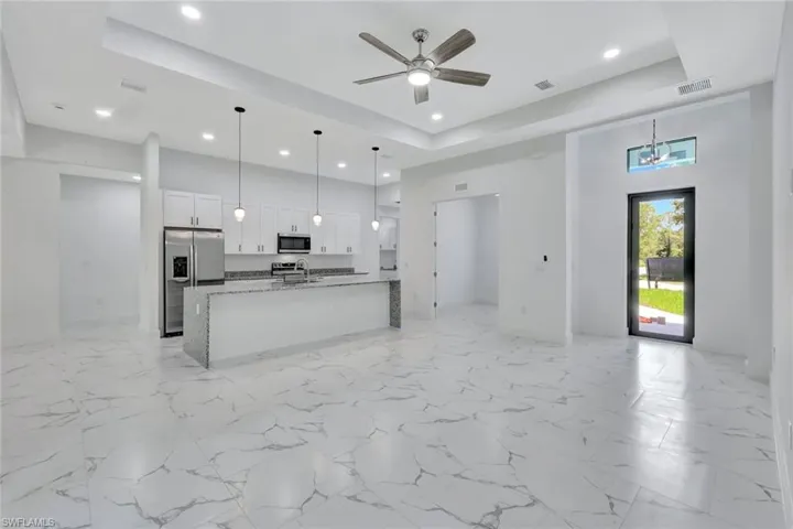 Kitchen featuring appliances with stainless steel finishes, open floor plan, recessed lighting, a raised ceiling, and white cabinets