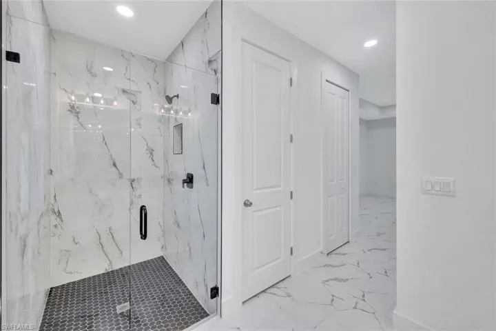Bathroom featuring marble finish floors, a marble finish shower, and recessed lighting