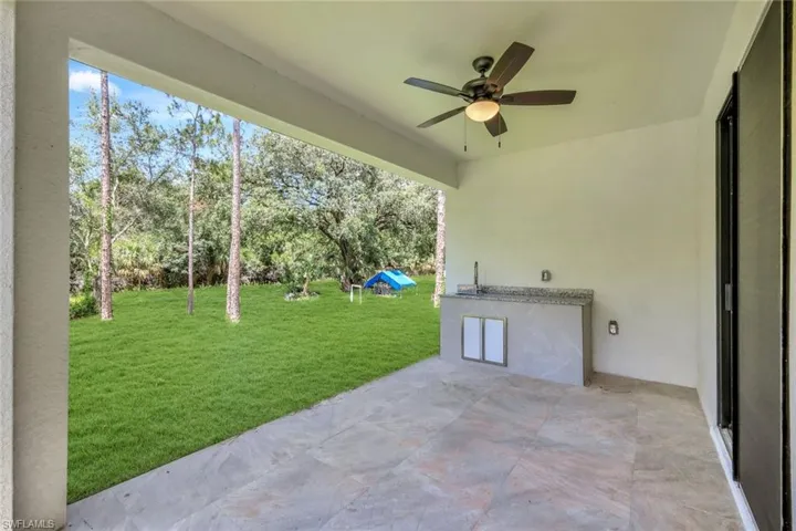 View of patio with a ceiling fan, view of scattered trees, and an outdoor kitchen