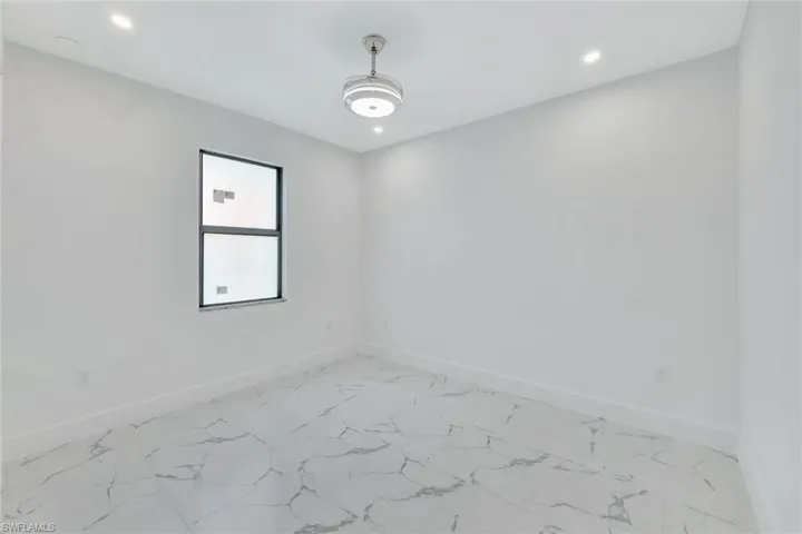Empty room featuring light marble finish floors and recessed lighting