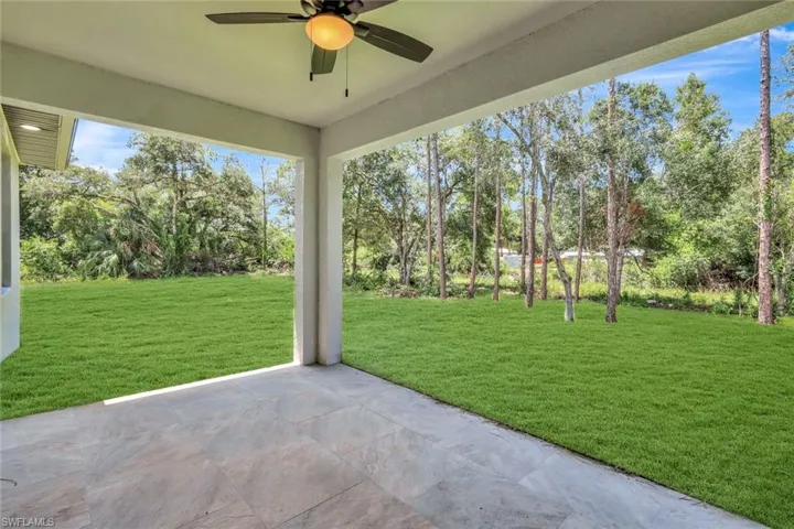 View of patio / terrace with ceiling fan and view of wooded area