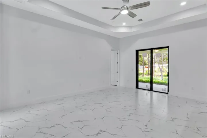Empty room featuring recessed lighting, a raised ceiling, ceiling fan, and marble look tiles