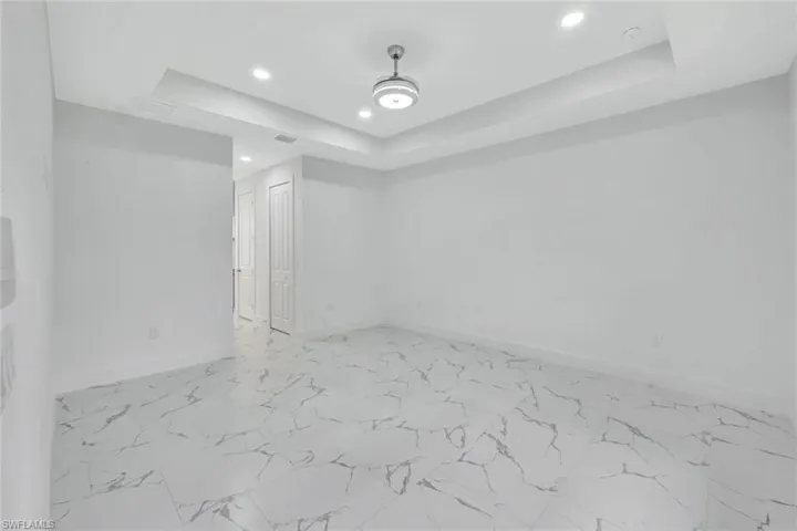 Spare room with recessed lighting, a raised ceiling, a smoke detector, and light marble finish flooring