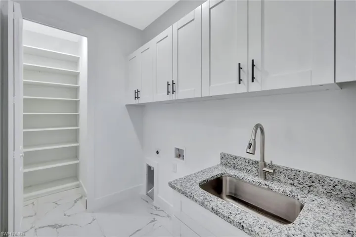 Washroom featuring cabinet space, hookup for an electric dryer, washer hookup, and light marble finish flooring