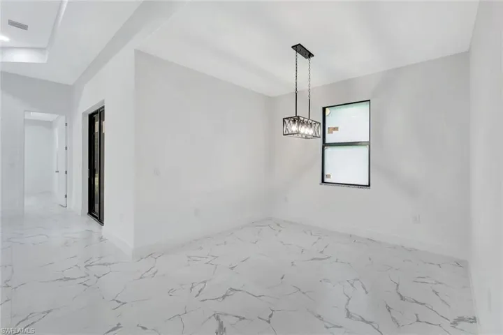 Spare room featuring light marble finish floors and baseboards