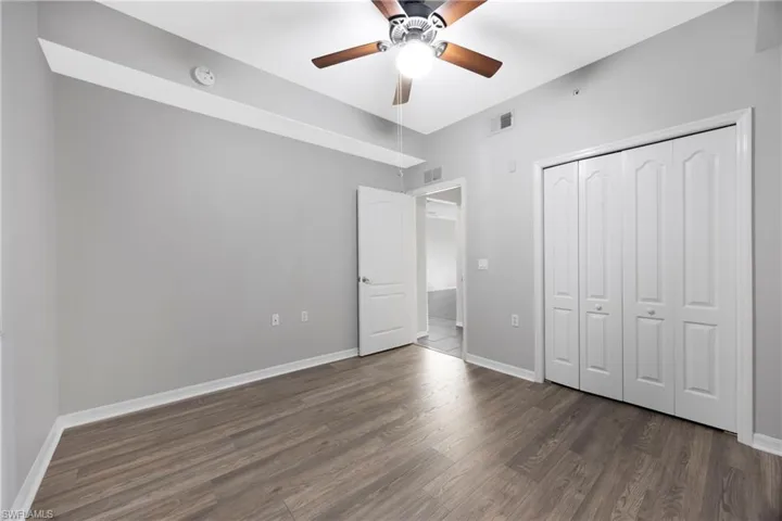 Unfurnished bedroom featuring dark wood-type flooring, a ceiling fan, and a closet