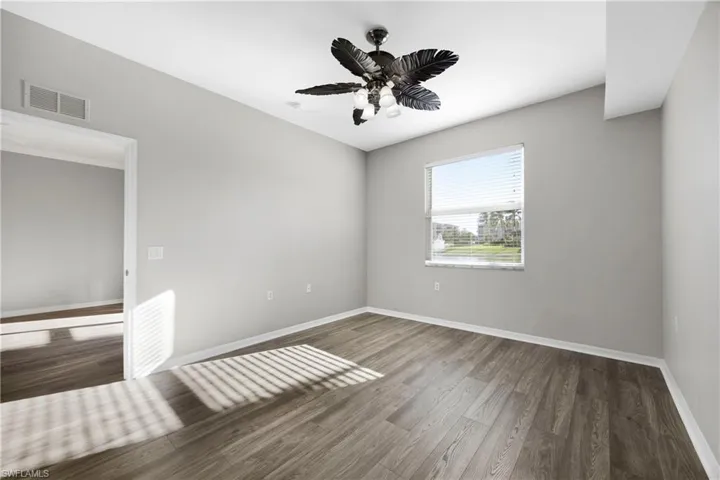 Unfurnished room featuring dark wood-style floors and ceiling fan