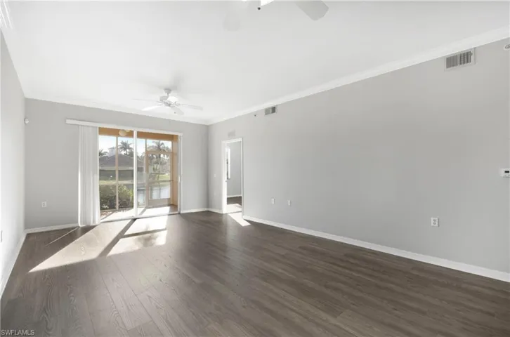 Unfurnished room featuring crown molding, dark wood-style floors, a water view, and ceiling fan