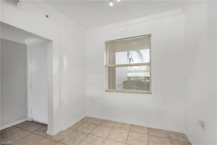 Spare room with ornamental molding and light tile patterned floors