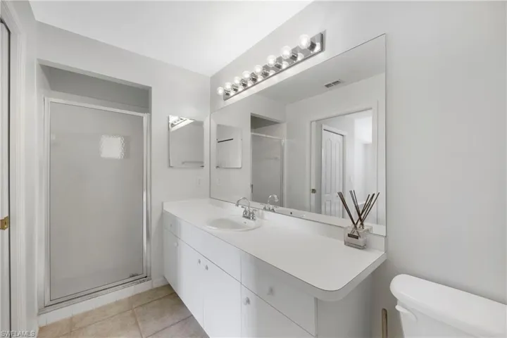 Full bath featuring a stall shower, light tile patterned floors, and vanity