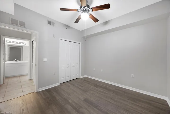 Unfurnished bedroom featuring dark wood-style floors, ceiling fan, and a closet