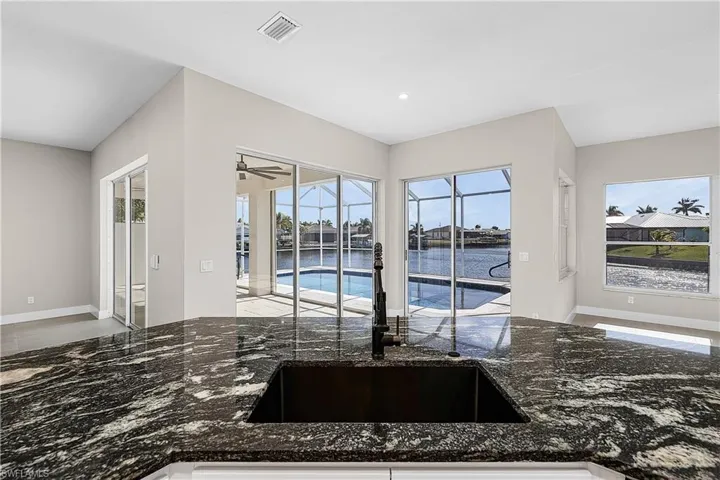 Kitchen with granite countertops, a water view, and recessed lighting