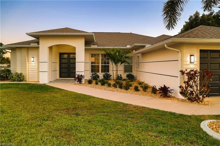 View of front of home with a lawn, a shingled roof, a garage, and stucco siding