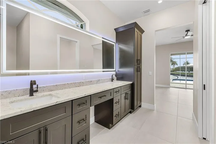Primary bathroom featuring double vanity and light porcelain tile flooring