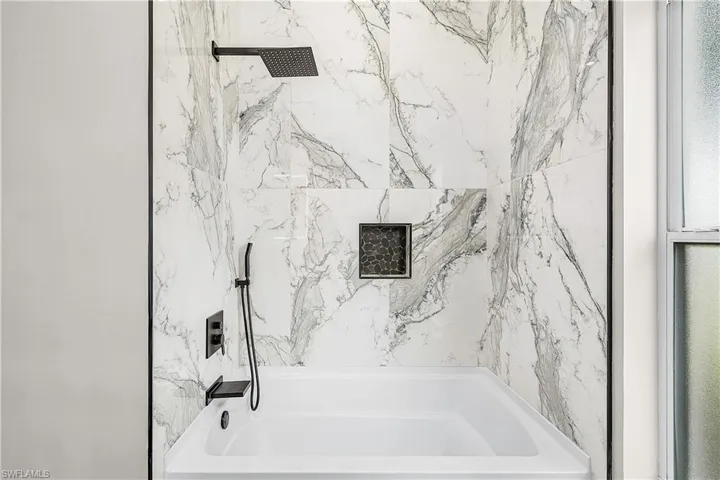 Full bathroom featuring a combined bath / shower with marble appearance