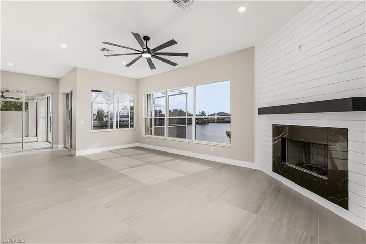 Family room with a fireplace, a water view, a ceiling fan, and recessed lighting