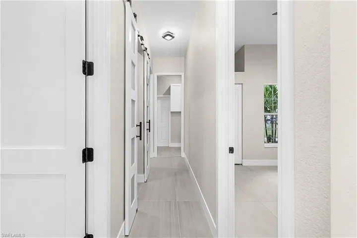 Hallway with a barn door and light porcelain tile flooring