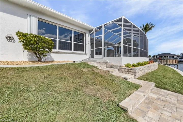 Back of property featuring screen enclosure, a lawn, a patio area, and stucco siding