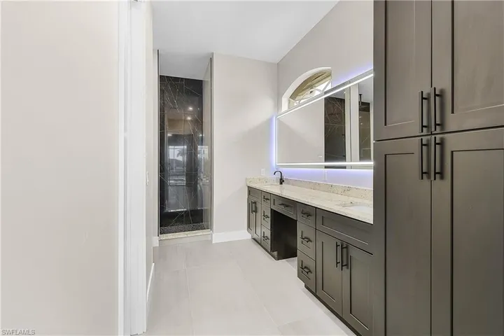 Primary bath with double vanity, a stall shower, and light porcelain tile flooring
