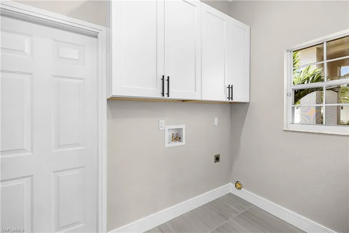 Laundry room with hookup for a washing machine, cabinet space, hookup for an electric dryer, and light porcelain tile flooring