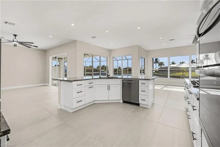 Kitchen with dark granite countertops, white cabinets, appliances with stainless steel finishes, and open floor plan